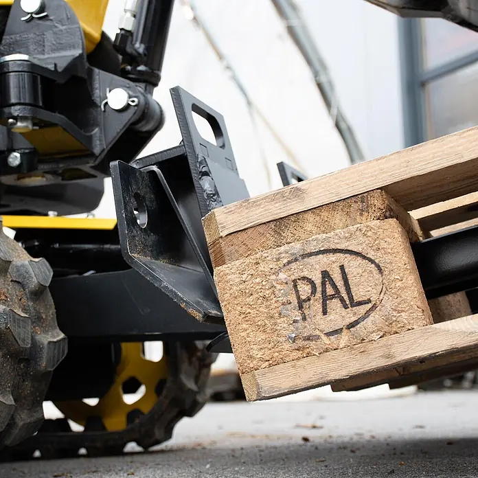 Bamato Palettengabel für MIB-600 -  - Schwarzer Metall-Palettengabel-Aufsatz an Baumaschine hebt Holzpalette.