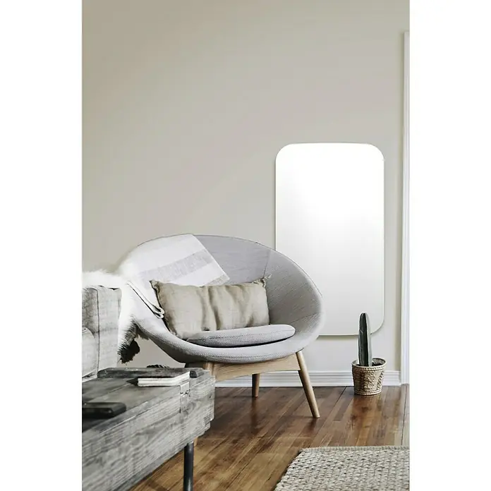 ClimaStar Speichersteinheizung WiFi Curve - Raumgröße bis ca. 18 m², Pearl White - Ein stilvolles Wohnzimmer mit einem modernen Spiegel an der Wand, einem bequemen Sessel und einem rustikalen Couchtisch.