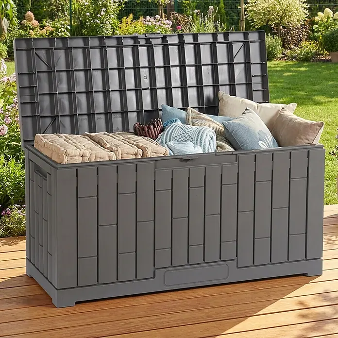 Dobar Garten-Aufbewahrungsbox Berlin - L x B x H: 112 x 39,5 x 52,5 cm, Kunststoff, Grau - Dunkelgraue Kunststoff-Gartenbox, offen mit Kissen und Decken, auf Holzterrasse im Garten.