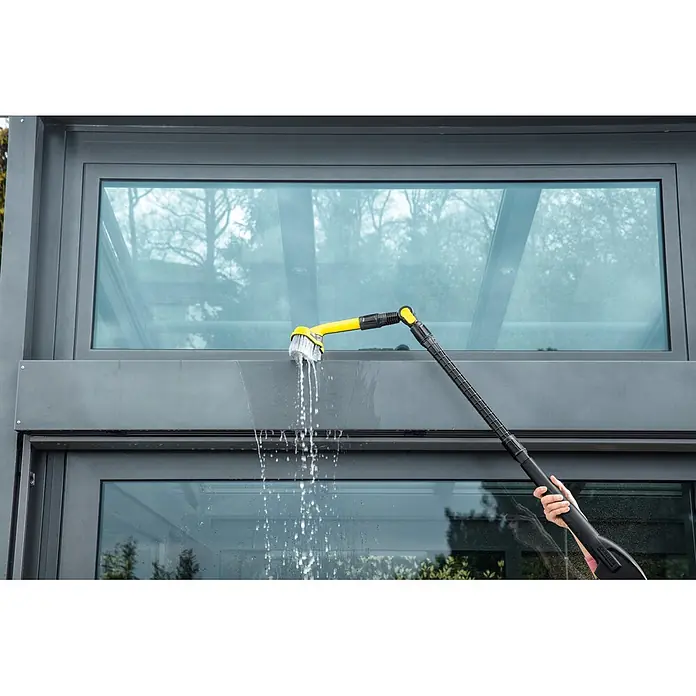 Kärcher Variogelenk - Passend für: Kärcher Hochdruckreiniger K2 - K7 - Ein gelb-schwarzer Kärcher Teleskop-Sprühbesen reinigt ein großes Außenfenster, Wasser spritzt aus dem Bürstenkopf.