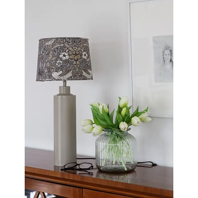 PR Home Tischleuchte Solo - 40 W, E27 - Eine Tischlampe mit taupefarbenem Sockel und gemustertem Lampenschirm mit Vögeln und Blumen auf einem Holz-Sideboard.