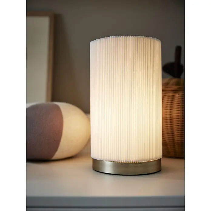 PR Home Tischleuchte Dora - 25 W, E27 - Beleuchtete zylindrische Tischlampe mit plissiertem weißem Schirm und Messingsockel, die warmes Licht abgibt.