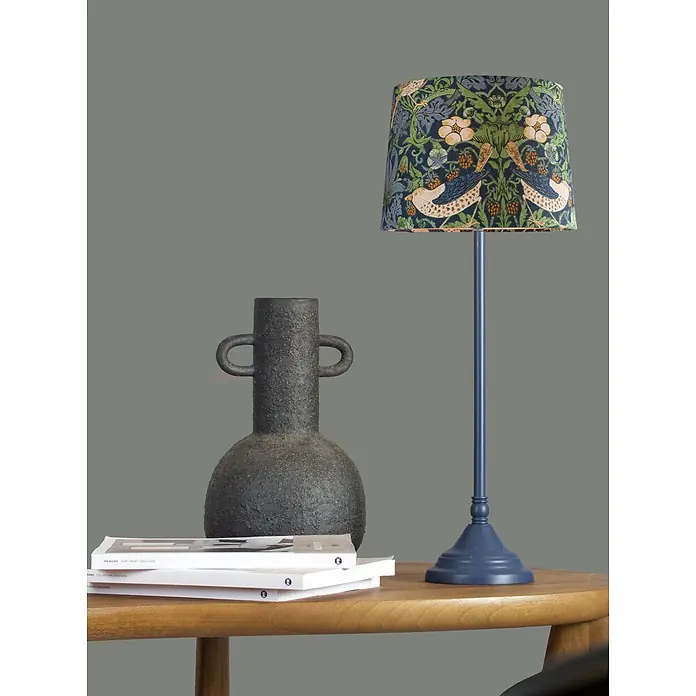 PR Home Tischleuchte Tove - 40 W, E27 - Blaue Tischlampe mit gemustertem Lampenschirm (Vögel, Blumen), neben dunkler, strukturierter Vase auf Holztisch.