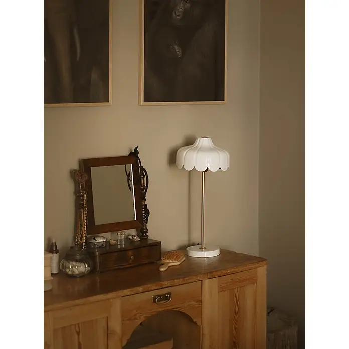 PR Home Tischleuchte Tischleuchte Wells - 25 W, E27 - Weiße Tischleuchte mit gewelltem Schirm und goldenem Stiel auf einer Holzkommode.