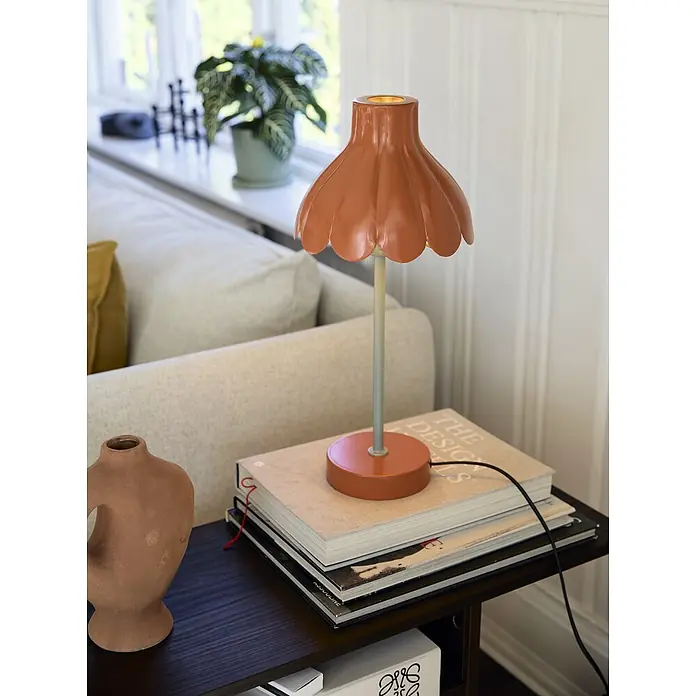 PR Home Tischleuchte Wera - 0,6 W, E27 - Terrakotta-Tischlampe mit gewelltem Schirm und hellgrünem Stiel auf einem Beistelltisch.