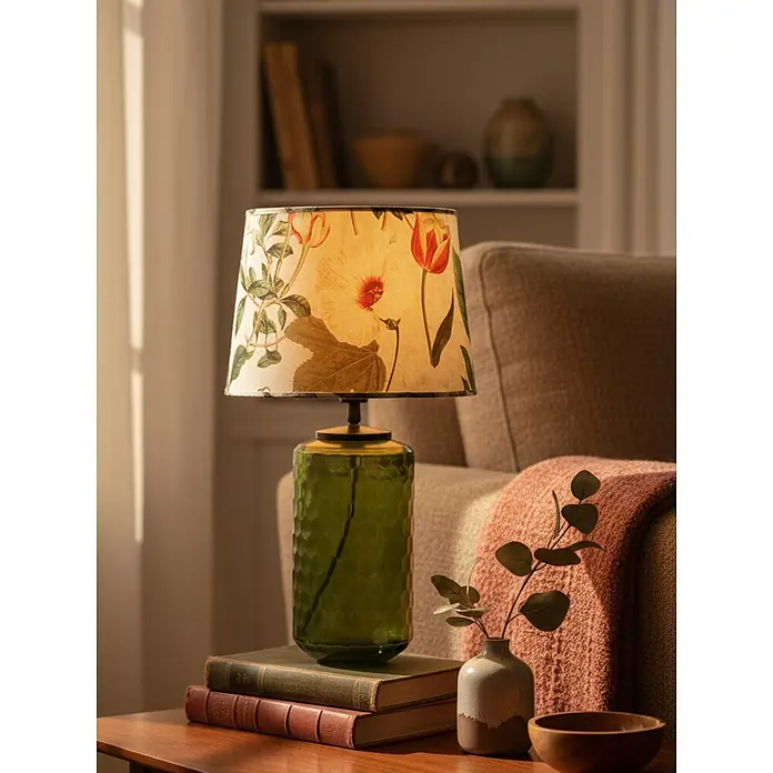 PR Home Tischleuchte Gabby - 40 W, E27 - Beleuchtete Blumenschreibtischlampe mit grünem strukturiertem Glassockel auf einem Holzbeistelltisch.