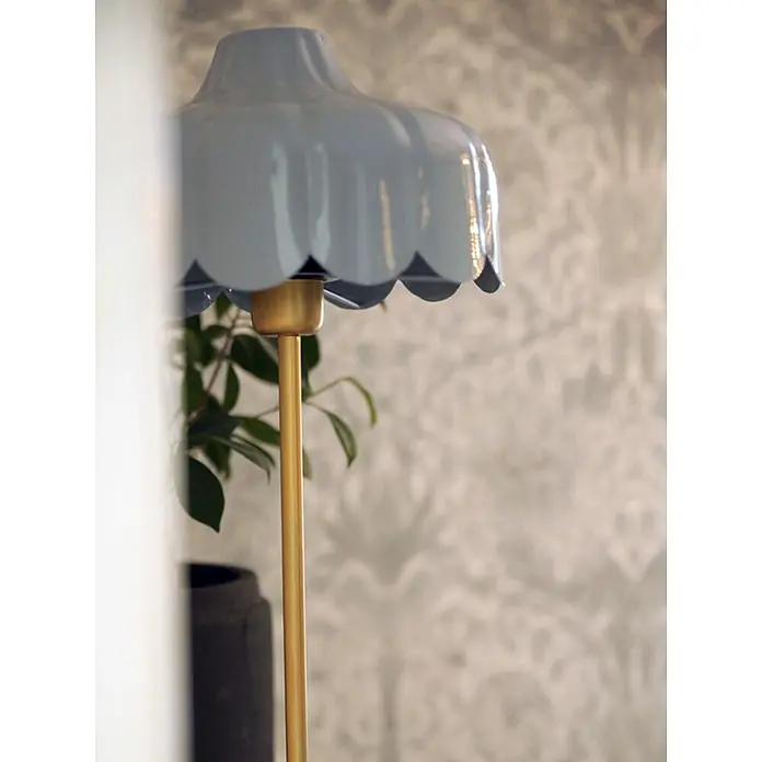 PR Home Tischleuchte Wells - 25 W, E27 - Hellblaue Lampe mit gewelltem Schirm und goldenem Ständer, in einem Raum mit gemusterter Tapete.