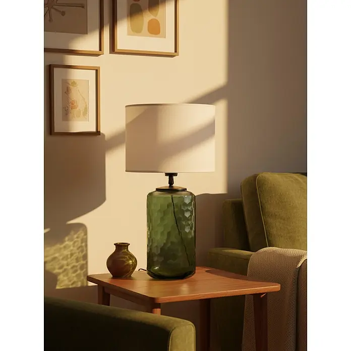 PR Home Tischleuchte Gabby - 40 W, E27 - Tischlampe mit grünem sechseckigem Glassockel und weißem zylindrischem Schirm, auf einem Beistelltisch zwischen grünen Sesseln.