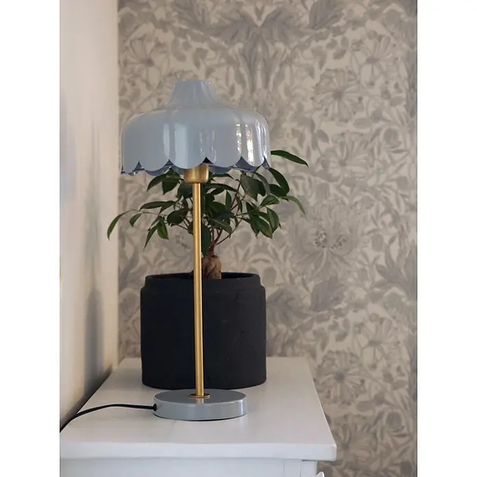 PR Home Tischleuchte Wells - 25 W, E27 - Hellblaue Tischlampe mit gewelltem Schirm, goldenem Stiel und grauem Fuß, neben einer Topfpflanze.