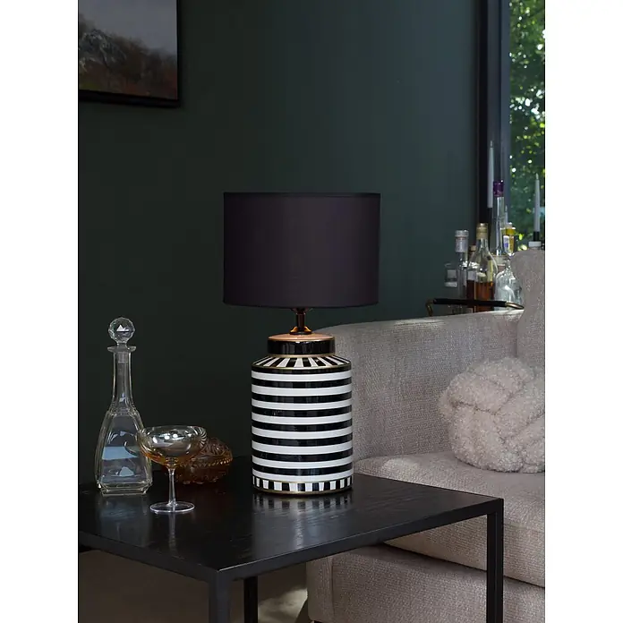 PR Home Tischleuchte 48cm - 40 W, E27 - Schwarz-weiß gestreifte Tischlampe mit schwarzem Schirm, auf einem dunklen Beistelltisch neben einem hellen Sofa.