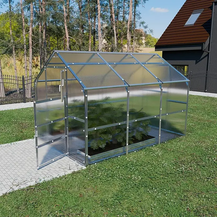 Klasika Greenhouses Gewächshaus Bernard Klasika - Außenmaß inkl. Dachüberstand (B x T): 235 x 300 cm, Material Seitenwand: Kunststoff, 4 mm, Silbergrau - Transparentes Gewächshaus mit silbernem Metallrahmen, Pflanzen im Inneren, in einem Garten mit gepflastertem Weg.