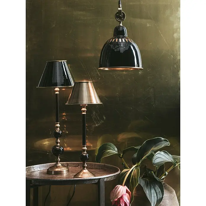 PR Home Tischleuchte Abbey - 40 W - Elegante schwarze und messingfarbene Tisch- und Pendelleuchten auf einem rustikalen Tisch mit einer Pflanze.