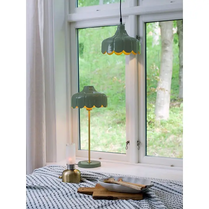 PR Home Tischleuchte Wells - 25 W, E27 - Grüne Hänge- und passende Tischlampe mit gewelltem Rand, beleuchtet auf einer Fensterbank, mit kleiner Messinglaterne.