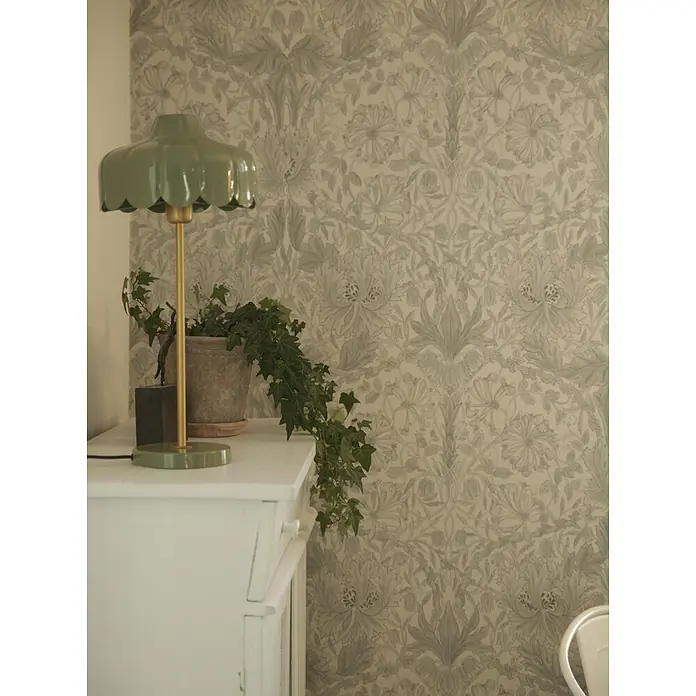 PR Home Tischleuchte Wells - 25 W, E27 - Grüne Wellenlampe mit goldenem Stiel auf weißem Schrank, mit Efeupflanze und floraler Tapete.