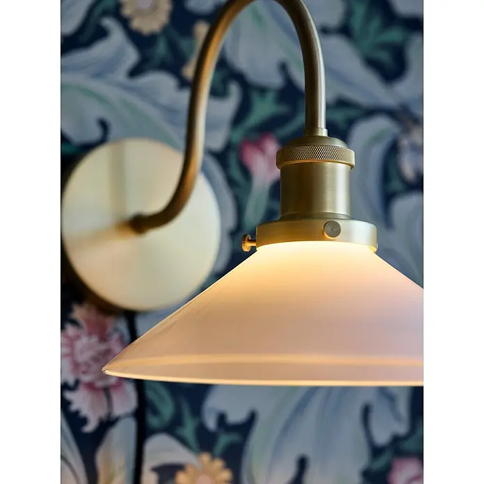 PR Home Wandleuchte Axel - 15 W, E27 - Wandleuchte aus Messing mit mattiertem Glasschirm an einer gemusterten Wand, spendet warmes Licht.