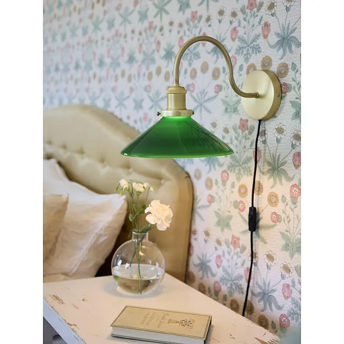 PR Home Wandleuchte Axel - 25 W, E27 - Wandleuchte aus Messing mit grünem Glasschirm, über einem Nachttisch im Schlafzimmer montiert.