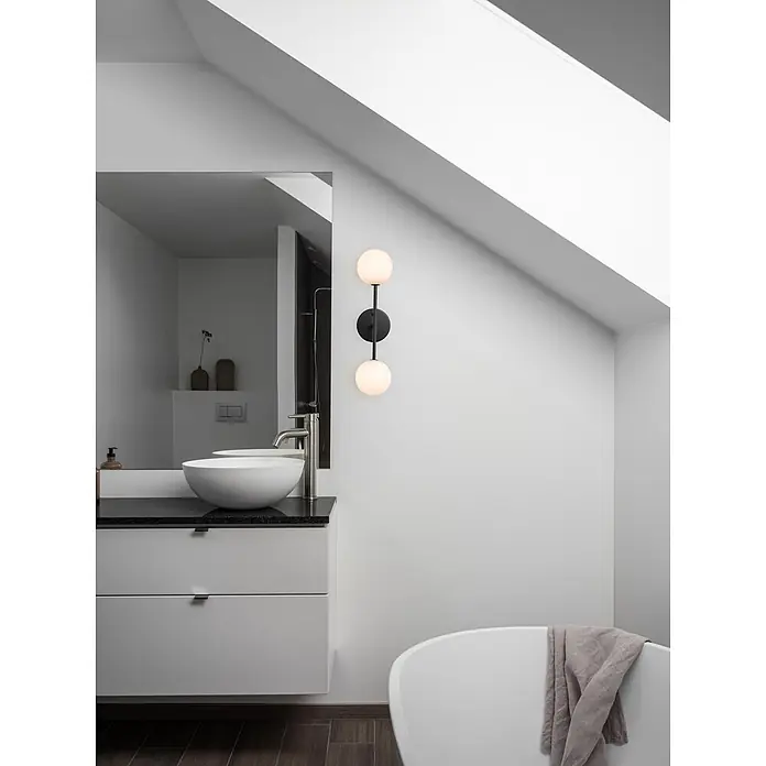 PR Home Wandleuchte Wandleuchte Sigma D - 25 W, G9 - Modernes Badezimmer mit weißem Waschtisch, Aufsatzwaschbecken, schwarzer Arbeitsplatte und schwarzer Wandleuchte. Eine weiße Badewanne ist sichtbar.
