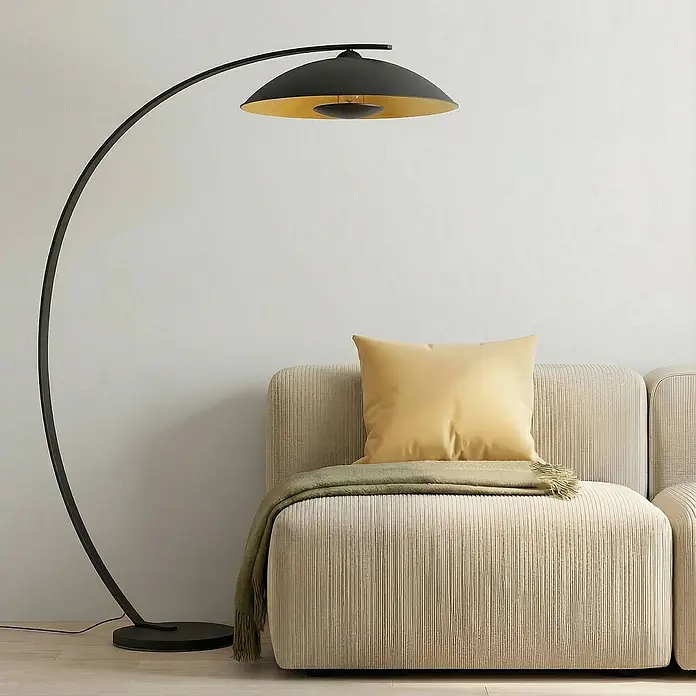 Lindby Stehleuchte Emilienne - schwarz, schwarz, E27 - Schwarze Bogen-Stehleuchte mit Goldschirm über beigem Cord-Modulsofa mit Kissen.