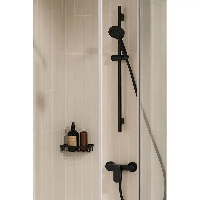 Roca Grifo de ducha Cala - Negro, Mate - Grifería de ducha negra y estante esquinero con botellas en una ducha moderna con azulejos.
