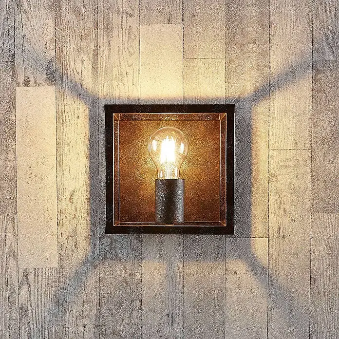 Lindby Wandleuchte Emin - braun / rost, braun / rost, E27 - Quadratische Wandleuchte aus dunklem Metall mit goldener Innenseite und sichtbarer Edison-Glühbirne an einer Holzwand.
