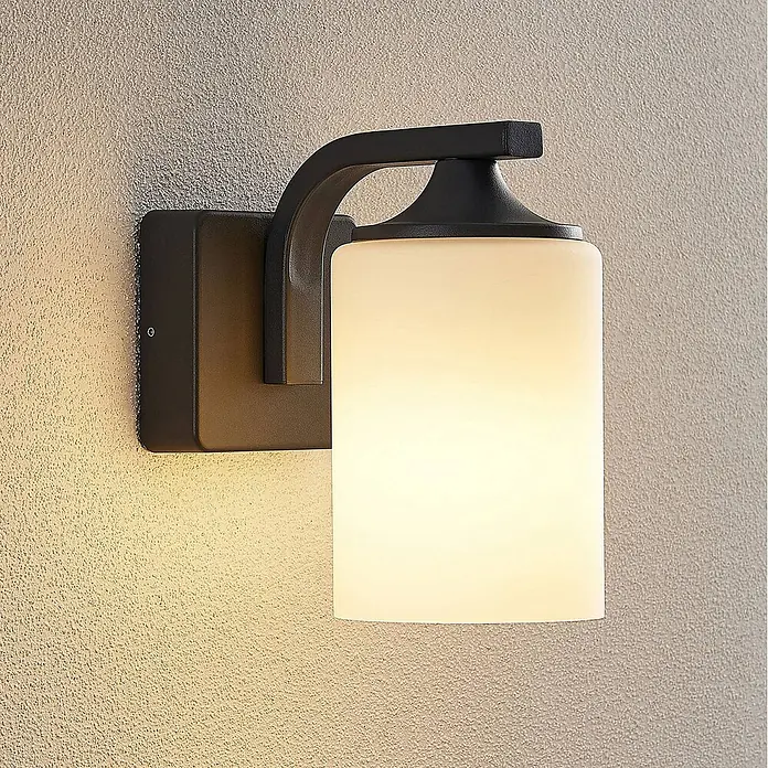 Lindby Außenwandleuchte Yannis - 21 x 11,8 x 21,2 cm, alu / grau / zink, creme / amber, IP43 - Schwarze Wandleuchte aus Metall mit geschwungenem Arm und zylindrischem Opalglasschirm, spendet warmes Licht.