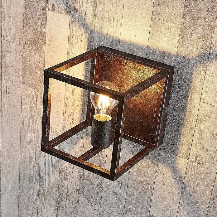 Lindby Wandleuchte Emin - braun / rost, braun / rost, E27 - Industrielle Würfel-Wandleuchte mit rostigem Metallrahmen und sichtbarer Glühbirne an Holzwand.
