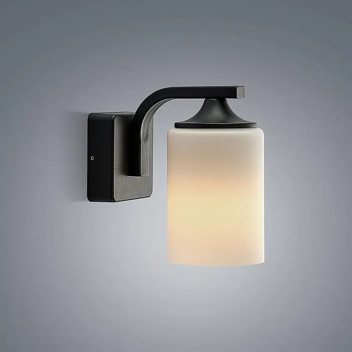 Lindby Außenwandleuchte Yannis - 21 x 11,8 x 21,2 cm, alu / grau / zink, creme / amber, IP43 - Wandleuchte mit mattschwarzem Metallrahmen und beleuchtetem zylindrischem Schirm aus mattiertem Glas.