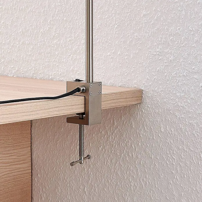 Lindby Klemmleuchte Hanilo - L x B x H: 37 x 4 x 80 cm, Farbe Gehäuse: alu / grau / zink - Silberne Metall-Lampenklemme an hellem Holzschreibtisch, mit Lampenstab und Stromkabel.