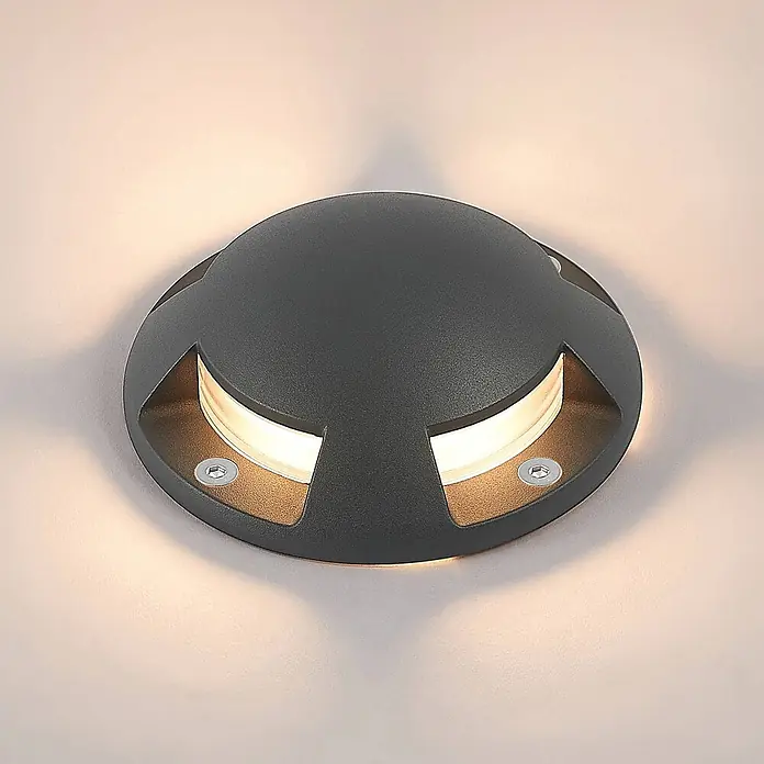Lindby LED-Gartenstrahler Huban - 3.000 K - Runde, dunkelgraue Außenleuchte mit strukturierter Oberfläche und zwei gewölbten Öffnungen, die warmweißes Licht abgeben.