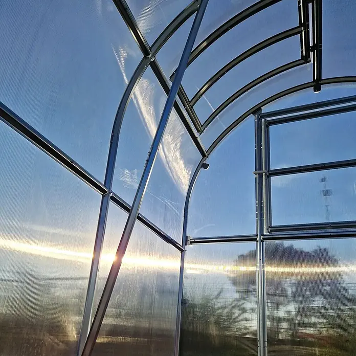 Klasika Greenhouses Gewächshaus Slim Klasika - Außenmaß inkl. Dachüberstand (B x T): 200 x 800 cm, Material Seitenwand: Kunststoff, 6 mm, SIlbergrau - Gewächshaus-Innenansicht mit Metallrahmen und transparenten Wellplatten, die Sonne scheint hindurch.