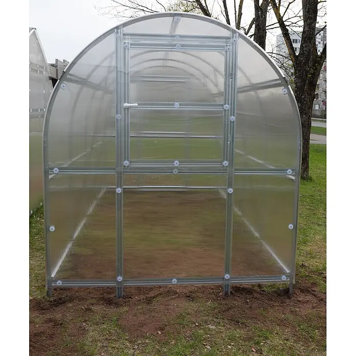 Klasika Greenhouses Gewächshaus Slim Klasika - Außenmaß inkl. Dachüberstand (B x T): 200 x 800 cm, Material Seitenwand: Kunststoff, 6 mm, SIlbergrau - Ein montiertes Gewächshaus aus transparenten Polycarbonatplatten und einem silbernen Metallrahmen, stehend auf brauner Erde und grünem Gras.