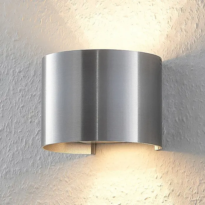 Arcchio Wandleuchte Zuzana - alu / grau / zink, G9 - Gebürstete Metall-Wandleuchte, die warmes Licht nach oben und unten auf eine strukturierte Wand wirft.