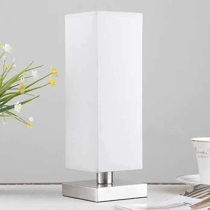 Lindby Tischleuchte Julina - L x B x H: 12 x 12 x 35 cm, alu / grau / zink, alu / grau / zink, E14 - Weiße quadratische Tischlampe mit einem Sockel aus gebürstetem Silber, auf einem Tisch stehend.