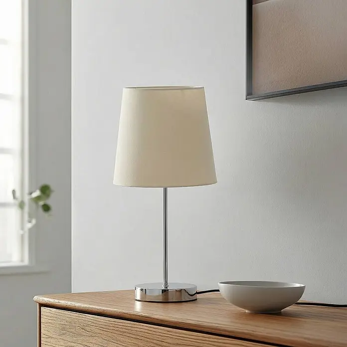 Lindby Tischleuchte Leza - chrom / silber, weiß / opal, E14 - Eine Tischleuchte mit beigem Stoffschirm und verchromtem Metallsockel, auf einer Holzoberfläche.