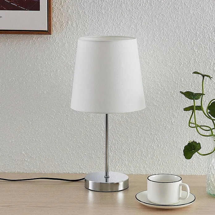 Lindby Tischleuchte Leza - chrom / silber, weiß / opal, E14 - Moderne Tischlampe mit weißem Stoffschirm und Chromfuß auf einem Holzschreibtisch.