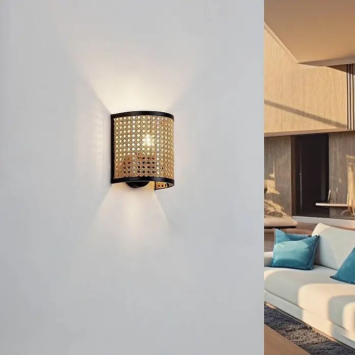 Lindby Wandleuchte Yaelle - Holz hell, E27 - Wandleuchte mit geflochtenem Rattanschirm und schwarzem Rahmen in einem modernen Wohnzimmer.