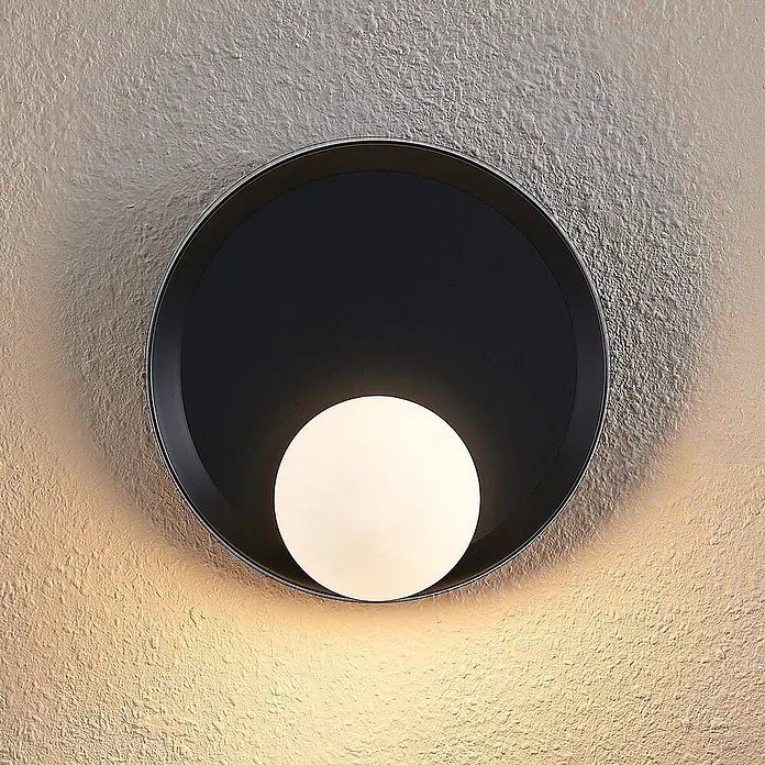 Lucande Wandleuchte Andelina - L x B x H: 13 x 30 x 30 cm, schwarz, G9 - Runde schwarze Wandleuchte mit weißer Kugel, die warmes Licht auf eine strukturierte Wand wirft.