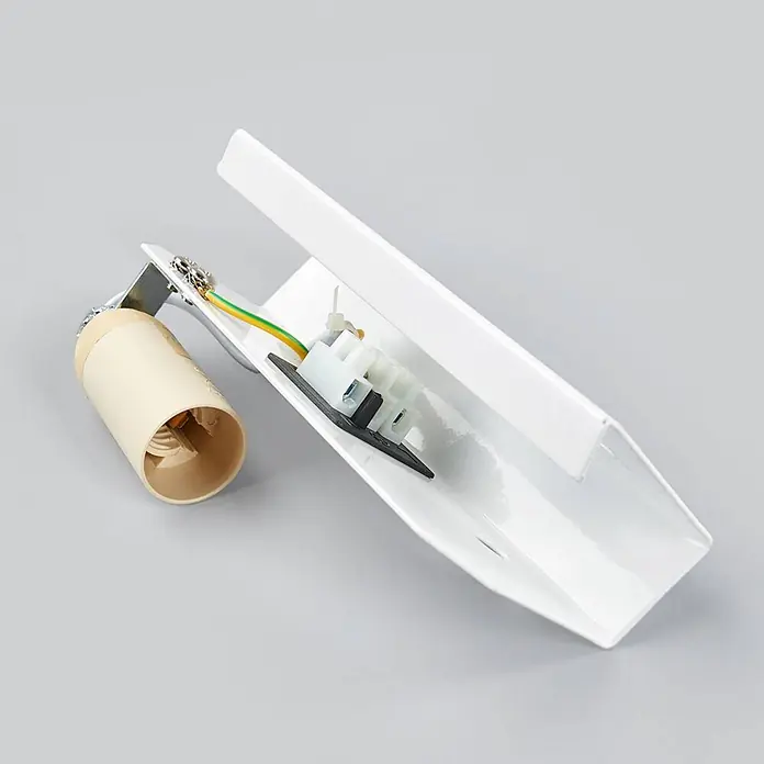Lindby Wandleuchte Kolja - messing / gold, E14 - Interne Verkabelung und Komponenten einer weißen Metallleuchte mit beigem Lampenfassung, grün-gelbem Erdungskabel und Klemmenblock.
