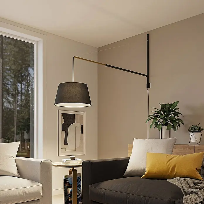 Lucande Wandleuchte Beleza - schwarz, schwarz, E27 - Schwarze und messingfarbene Schwenkarm-Wandleuchte mit dunklem Stoffschirm, die sich über ein Sofa im Wohnzimmer erstreckt.