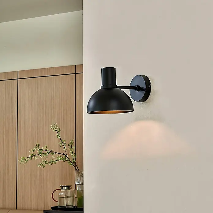 Lucande Wandleuchte Mostrid - L x B x H: 24 x 17 x 19,3 cm, schwarz, schwarz, E27 - Mattschwarze Wandleuchte mit Kuppelschirm, wirft warmes Licht auf eine helle Wand.