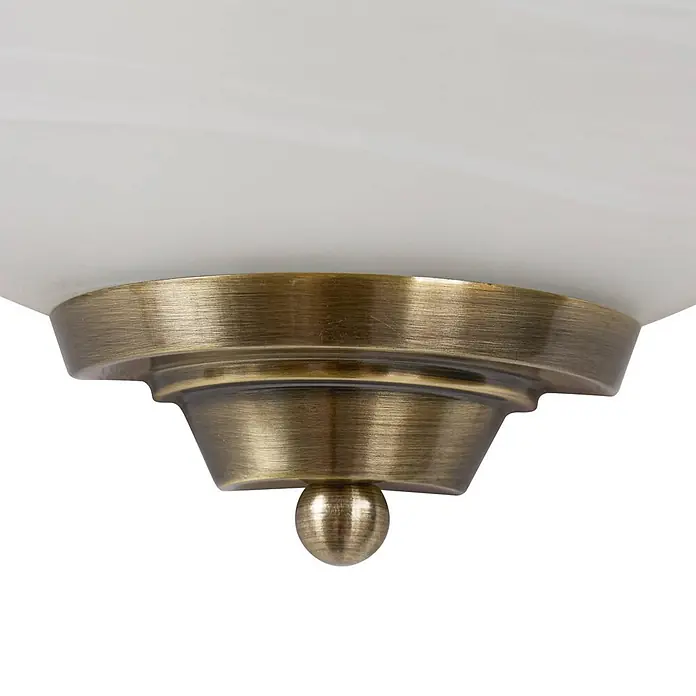 Lindby Wandleuchte Irimia - bronze / altmessing, E27 - Nahaufnahme einer Deckenleuchte mit weißem Marmorglas-Schirm und antik-bronzefarbenem Metallsockel mit Endstück.