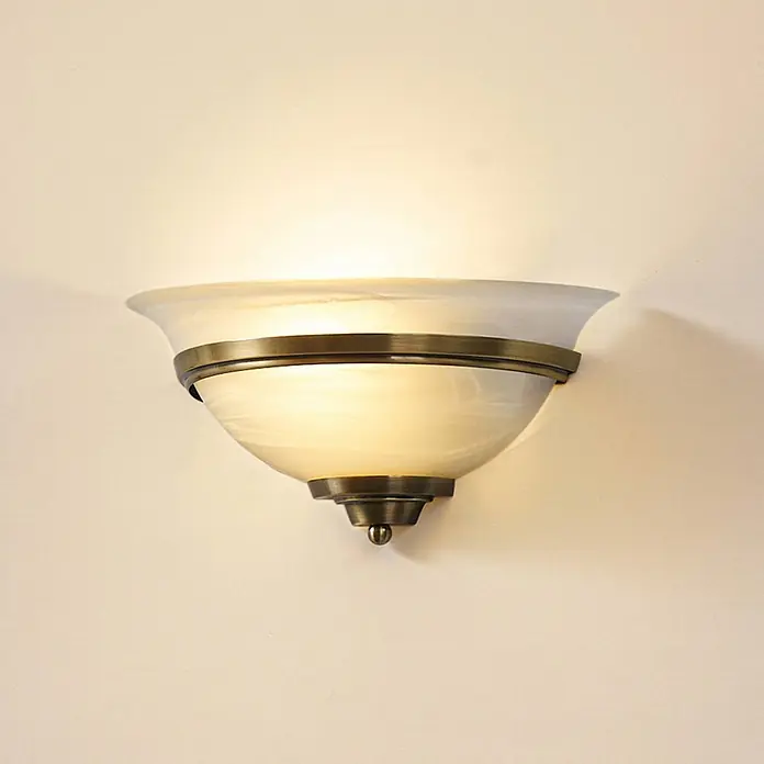 Lindby Wandleuchte Irimia - bronze / altmessing, E27 - Beleuchtete Wandleuchte mit Milchglas und antikem Messing, die warmes Licht an eine Wand wirft.