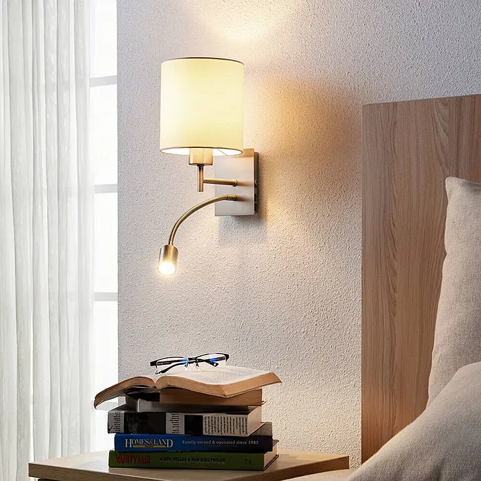 Lindby Wandleuchte Camilo - alu / grau / zink, E27 - Wandleuchte mit Stoffschirm, flexiblem Leselicht und USB-Anschlüssen, über einem Nachttisch montiert.
