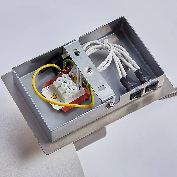 Lindby Wandleuchte Camilo - alu / grau / zink, E27 - Inneransicht einer silbernen Metall-Verbindungsbox mit weißen Kabeln, Klemmen, einem gelb-grünen Erdungskabel und zwei schwarzen Schaltern.