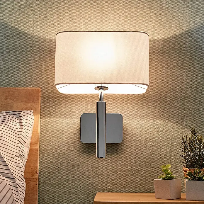 Lucande Wandleuchte Jettka - chrom / silber, E27 - Wandleuchte mit rechteckigem Stoffschirm und Chromfuß, neben einem Bett montiert.