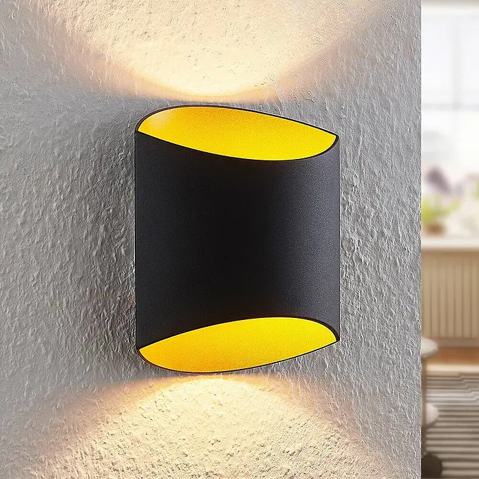 Arcchio Wandleuchte Vilja - schwarz, G9 - Schwarze Wandleuchte mit gelbem Inneren, wirft warmes Licht nach oben und unten auf eine strukturierte Wand.
