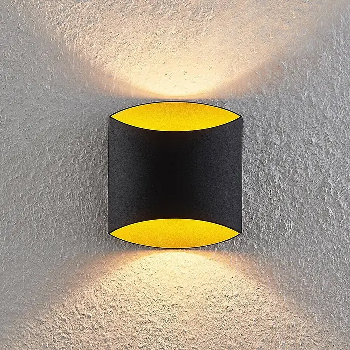 Arcchio Wandleuchte Vilja - schwarz, G9 - Schwarze Wandleuchte mit goldgelbem Inneren auf einer strukturierten Wand, wirft warmes Licht nach oben und unten.
