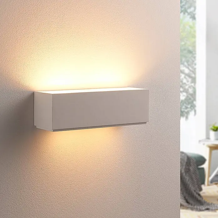 Lindby Wandleuchte Benno - L x B x H: 9 x 29 x 9 cm, weiß / opal, G9 - Weiße rechteckige Wandleuchte, montiert an einer strukturierten Wand, strahlt warmes Licht nach oben und unten. In einem modernen Raum.