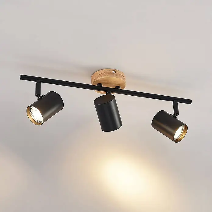 Lindby Deckenleuchte Xiomara - schwarz, GU10 - Schwarzer Deckenstrahler aus Metall mit drei verstellbaren Köpfen, goldenen Innenseiten und einer Naturholzhalterung.