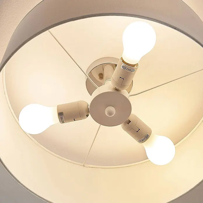 Lindby Deckenleuchte Mariat - weiß / opal, E27 - Innenansicht einer grauen Stoff-Deckenlampe mit drei E27 Fassungen, jede mit einer hellen LED-Glühbirne.